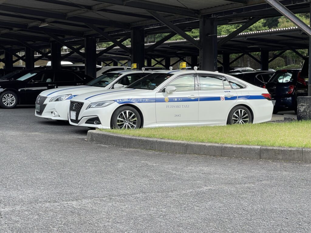 キングフィールズゴルフクラブの駐車場に並ぶクラウン個人タクシー2台と黒塗りハイヤー