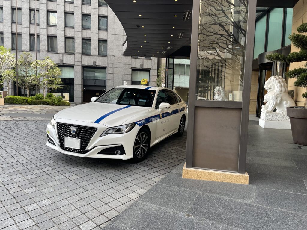 ザ・ペニンシュラ東京の正面エントランスで待機するFUJISAKI TAXIクラウン個人タクシー。広島から来られたお客様をお迎えし、東京ゴルフ倶楽部へ送迎。