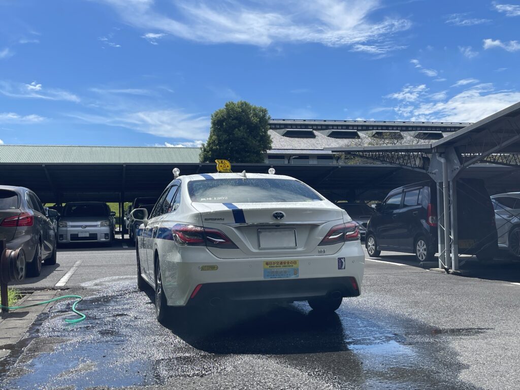 あおむらさきゴルフ倶楽部の駐車場で待機中に洗車するFUJISAKI TAXIのクラウン個人タクシー（ゴルフ送迎）