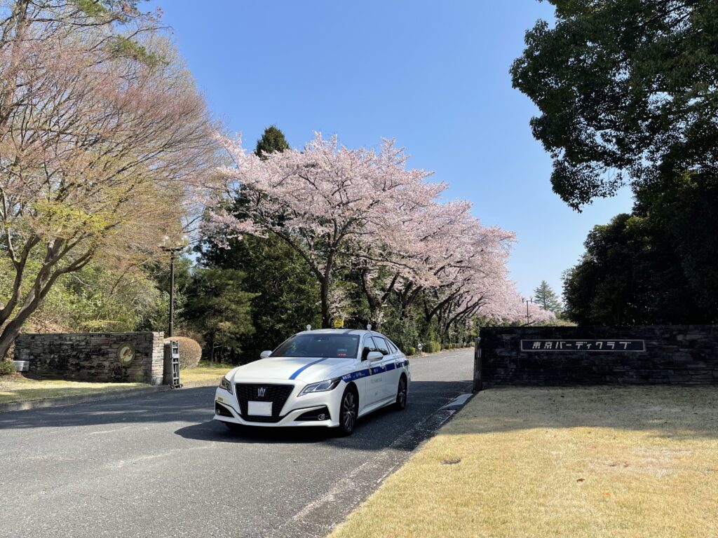 東京バーディクラブ（青梅市）の正門前、桜並木に停車する藤﨑タクシーのクラウン。東京発のゴルフ場送迎。