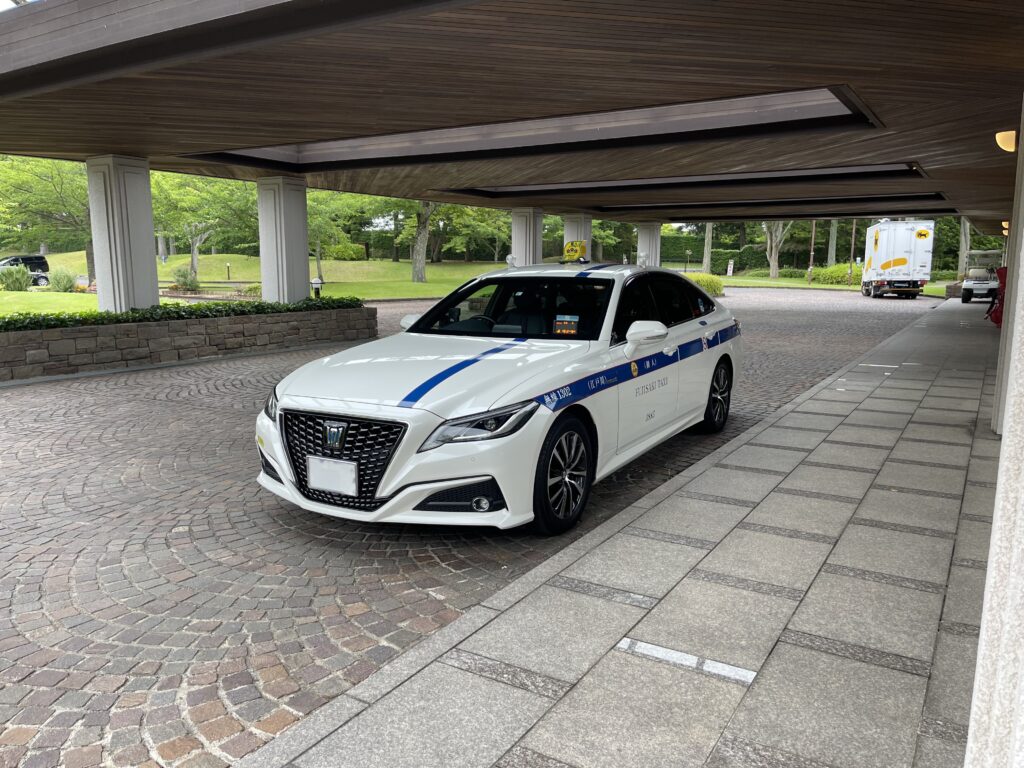 東急セブンハンドレッドクラブの車寄せで、キャディーバッグ積み込み完了後にお帰り待機する藤﨑タクシーのクラウン。ゴルフ場送迎の復路対応。